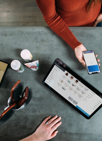 person holding smartphone beside tablet computer